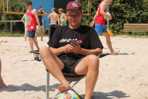 Das Bild zeigt den VolleyballFREAK beim Musik hören auf einem Beachvolleyball