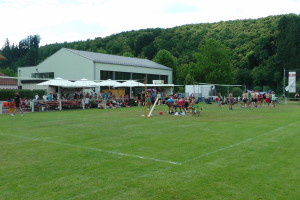 Das Bild zeigt 2 Volleyballspielfelder auf den Bettingen Open. Im Hintergrund sieht man den Bierwagen und Grillstand.