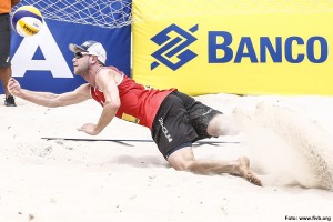 Das Foto zeigt Beachvolleyballer Stefan Windscheif bei der Abwehr im Sand.