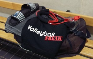 Das Foto zeigt eine gepackte Sportasche. Auf ihr ist ein VolleyballFREAK-T-Shirt. Ein Expander, Badelatschen und Handtuch.