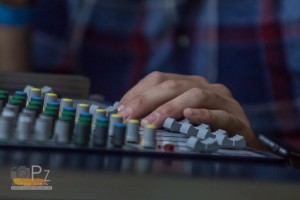 Das Foto zeigt die Hände an einem Mischpult. Dies symbolisiert einen Hallen DJ, der heizt mit Musik den Zuschauern ein.