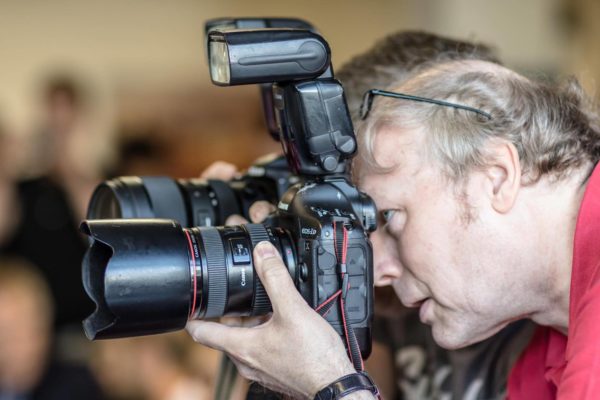 Das Foto zeigt einen Volleyball Fotografen mit einer hochwertigen Canon Fotokamera.