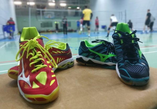 Das Foto zeigt neue Volleyballschuhe 2018: Mizunos Wave Lightning Z4 und Wave Tornado X2. Im Hintergrund trainiert eine Volleyballmannschaft.