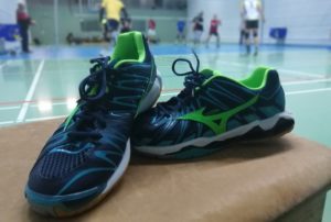 Das Foto zeigt die Die Mizuno Wave Tornado Wave X2 in blau/grün. Im Hintergrund sieht man ein Volleyballfeld, wo das Training läuft.