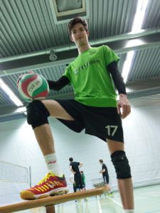 Das Foto zeigt VolleyballFREAK Oli mit den roten Mizuno Wave Lightning Z4 beim Test in der Sporthalle..Im Hintergrund sieht man ein Volleyballfeld mit Volleyballnetz und spielern.