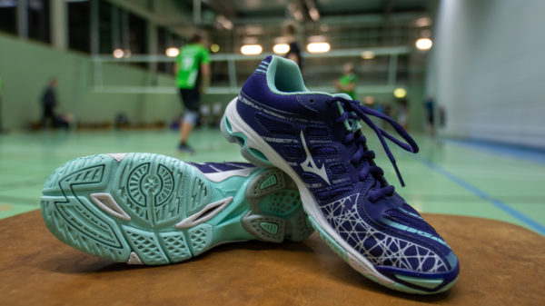 Ein Paar Volleyballschuhe Mizuno Wave Voltage vor einem Volleyballnetz